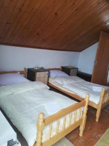 two twin beds in a bedroom with a wooden ceiling at Kupres Desktop - mountain house in Kupres