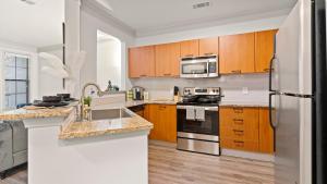 a kitchen with wooden cabinets and stainless steel appliances at “Essence” Condo in Buckhead in Atlanta
