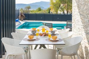 a table with food on it next to a pool at "Casa Mia" Luxury villa with heated swimming pool with jacuzzi in Šestanovac