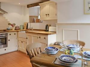 een keuken met een houten tafel met stoelen en borden erop bij Ash Cottage in Tideswell