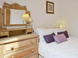 een slaapkamer met een bed, een dressoir en een spiegel bij Ash Cottage in Tideswell