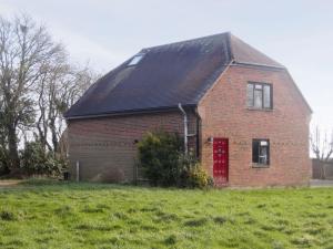 een rood bakstenen huis met een rode deur in een veld bij Greenwood Cottage in Sandown