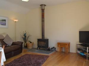 a living room with a wood stove in the corner at Wellys Wallow in Saint Kew