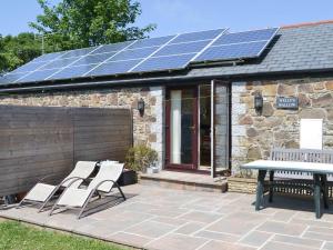a patio with two chairs and a table with solar panels at Wellys Wallow in Saint Kew