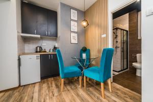 een keuken met een glazen tafel en blauwe stoelen bij Marcel Apartments in Belgrado