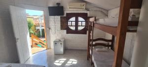a small room with two bunk beds and a window at Chalé Beija Flor in Praia do Frances