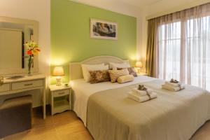 
a hotel room with a bed, table, dresser and mirror at Agrimia Holiday Apartments in Platanias
