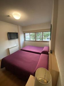 1 dormitorio con cama morada y ventana en Hotel Escuela Madrid en Madrid