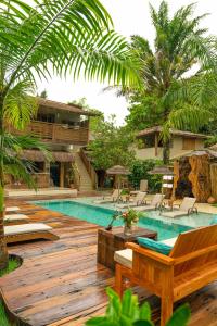 una piscina con una terraza de madera con sillas y una casa en Pousada Raízes do Brasil, en Trancoso