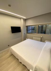 1 dormitorio con 1 cama blanca grande y TV de pantalla plana en Hotel Escuela Madrid en Madrid