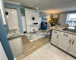 uma cozinha com armários brancos e uma sala de estar em Marylander Condominiums, 90 steps from the beach em Ocean City