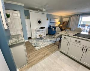 a kitchen with white cabinets and a living room at Marylander Condominiums, 90 steps from the beach in Ocean City