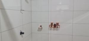 a bathroom with white tile walls and a mirror at Pousada Descobrindo a Vida in Brumadinho