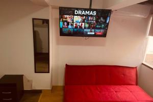 un sofá rojo en una habitación con TV en la pared en (27) Acogedor Dpto en Miraflores, en Lima
