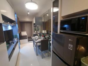 a kitchen and dining room with a table and a microwave at Cosy Luxy Coast Residences Staycation in Manila