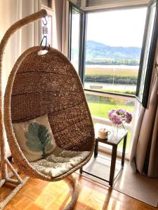 a wicker chair in a room with a large window at Rincon en el Rio Sella in Ribadesella