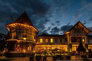 a large house with lights in front of it at night at Hotel Vila Inglesa in Campos do Jordão