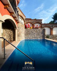 a swimming pool in a house with a stone wall at Hotel Real de los Alamos in Álamos