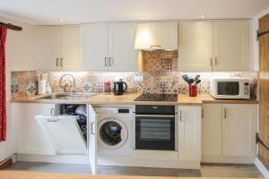 a kitchen with a washing machine and a microwave at Hollyhocks Cottage in Docking