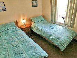 two twin beds in a bedroom with a window at Hollyhocks Cottage in Docking