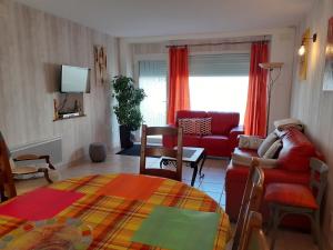 a living room with a red couch and a table at Gîte Carnot in Dompaire