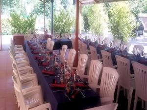 una mesa larga con sillas blancas y copas de vino en Ristorante Dosso, en Sigirino
