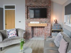 a living room with a brick fireplace with a tv at The Bunker in Otterburn