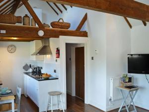 een keuken met witte muren en houten balken bij Honey Meadow Cottage in West Hoathley