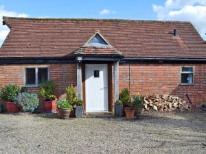 a brick house with a white door and potted plants at Honey Meadow Cottage in West Hoathley