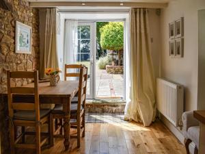 a dining room with a wooden table and a door at Bathurst Cottage in Scarcliffe