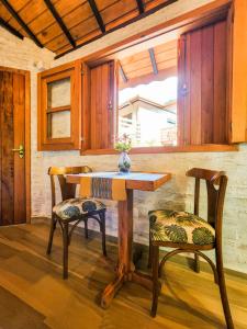 un tavolo in legno con due sedie e un vaso sopra di Pousada Cabana na Floresta - Monte Verde a Camanducaia