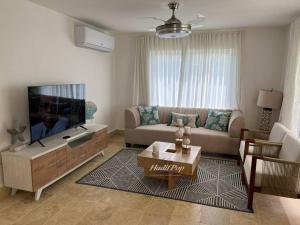 sala de estar con sofá y TV de pantalla plana en Exclusiva villa vacacional, en San Felipe de Puerto Plata