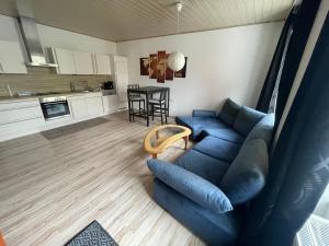 ein Wohnzimmer mit einem blauen Sofa und einer Küche in der Unterkunft City Appartement 4910 in Ried im Innkreis