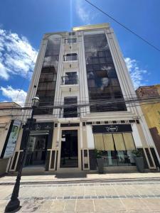 a tall white building with windows on a street at Comfy apartment, best location ! in Tarija