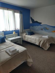 1 dormitorio con 2 camas y un mural de delfines en la pared en ROCAYAS HOME en Esquel