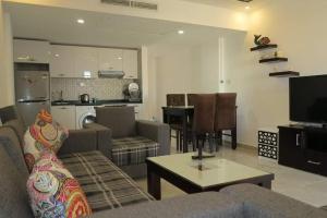 ポート・ガリブにあるMarina city port ghalib chaletのリビングルーム(ソファ、テーブル付)、キッチンが備わります。