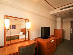 um quarto com uma secretária, uma televisão e uma cama em Hotel Tetora Otsu Kyoto em Otsu
