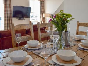 a wooden table with bowls and wine glasses on it at Harbourside Apartment in Anstruther