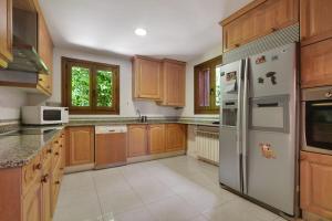a kitchen with wooden cabinets and a white refrigerator at Chalet Navacerrada Piscina Privada in Navacerrada