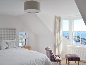 1 dormitorio con cama, ventana y silla en Harbourside Apartment, en Anstruther