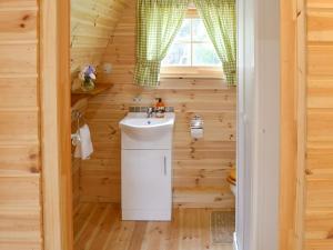 un baño en una cabaña de madera con lavabo en The Squirrels strelley Barn, en Woodham Mortimer