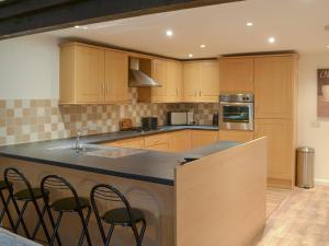 a kitchen with wooden cabinets and a counter with stools at Runhead Forge in Ryton