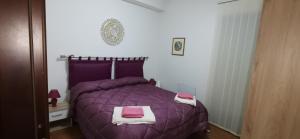 1 dormitorio con 1 cama morada y 2 toallas en SEGESTA - New Nouveau Bedding, en Salemi