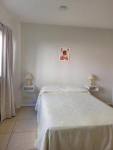 1 dormitorio blanco con 1 cama y 2 lámparas en PASAJE EN EL CENTRO DE LOMAS en Lomas de Zamora