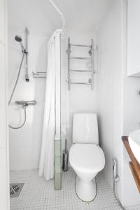 La salle de bains blanche est pourvue d'une douche et de toilettes. dans l'établissement WeHost Heart of Helsinki Studio with Top Amenities, à Helsinki
