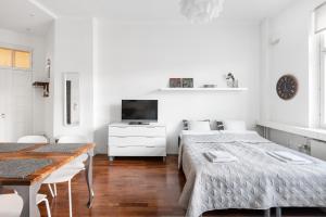 a white bedroom with two beds and a dining table at WeHost Heart of Helsinki Studio with Top Amenities in Helsinki