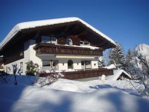 una casa con techo cubierto de nieve en la nieve en Ferienwohnung Kircher, en Obermaiselstein
