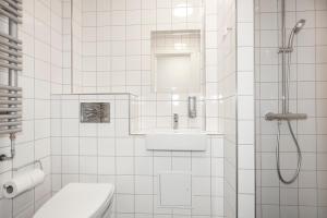a white tiled bathroom with a sink and a shower at Hotel Osted in Lejre