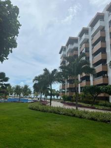un gran edificio de apartamentos con palmeras y un parque en Paraíso do Atlântico Club Residence, en Cabedelo