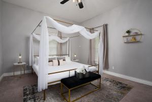 ein Himmelbett mit weißen Vorhängen in einem Schlafzimmer in der Unterkunft Modern 3 Bed, 2 Bath Home Minutes to Downtown & Alamodome in San Antonio